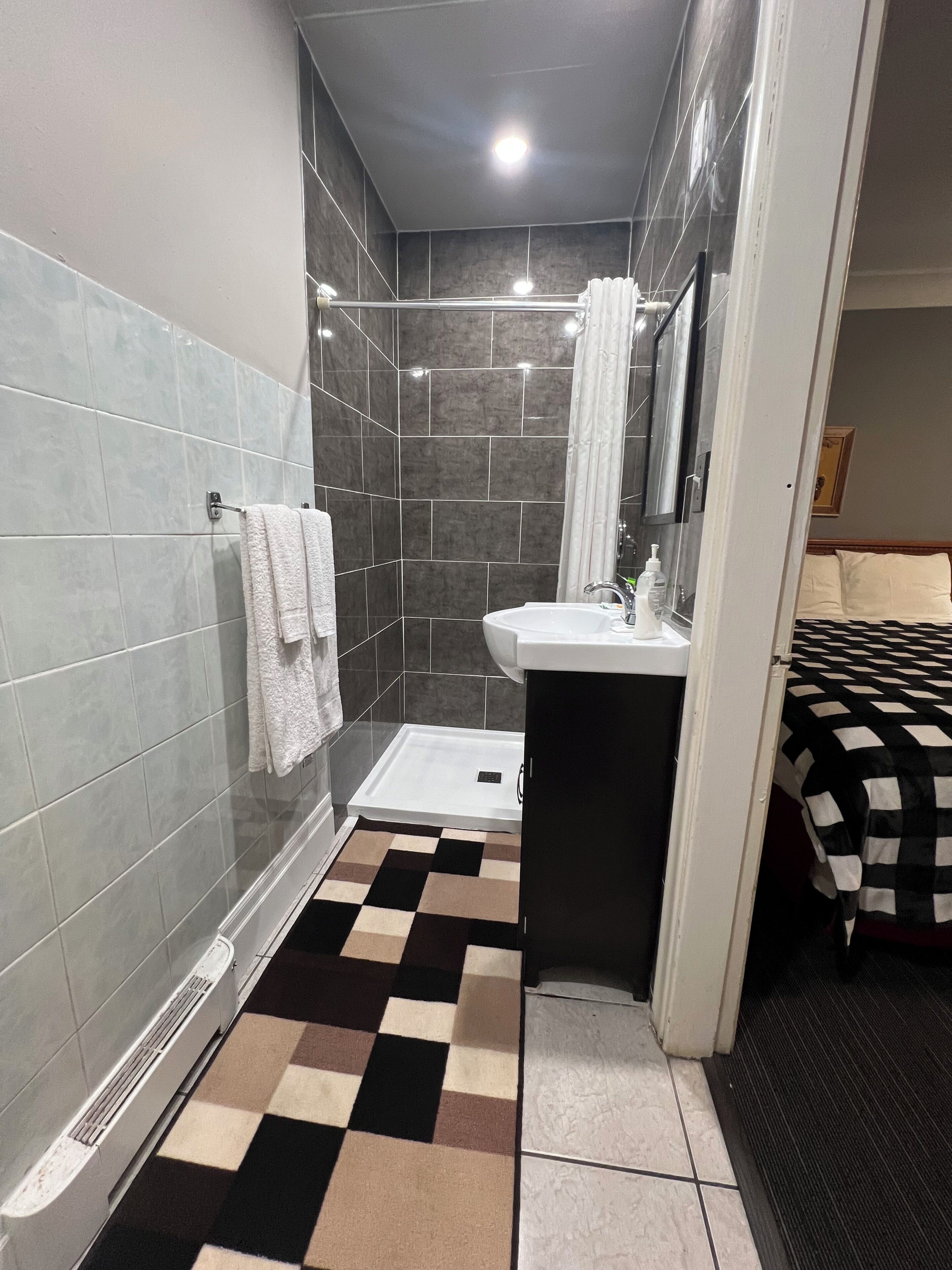 Een badkamer met een douche, wastafel en een geruite vloer.