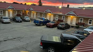 Un parking où sont garées plusieurs voitures et un bâtiment avec un toit rouge.