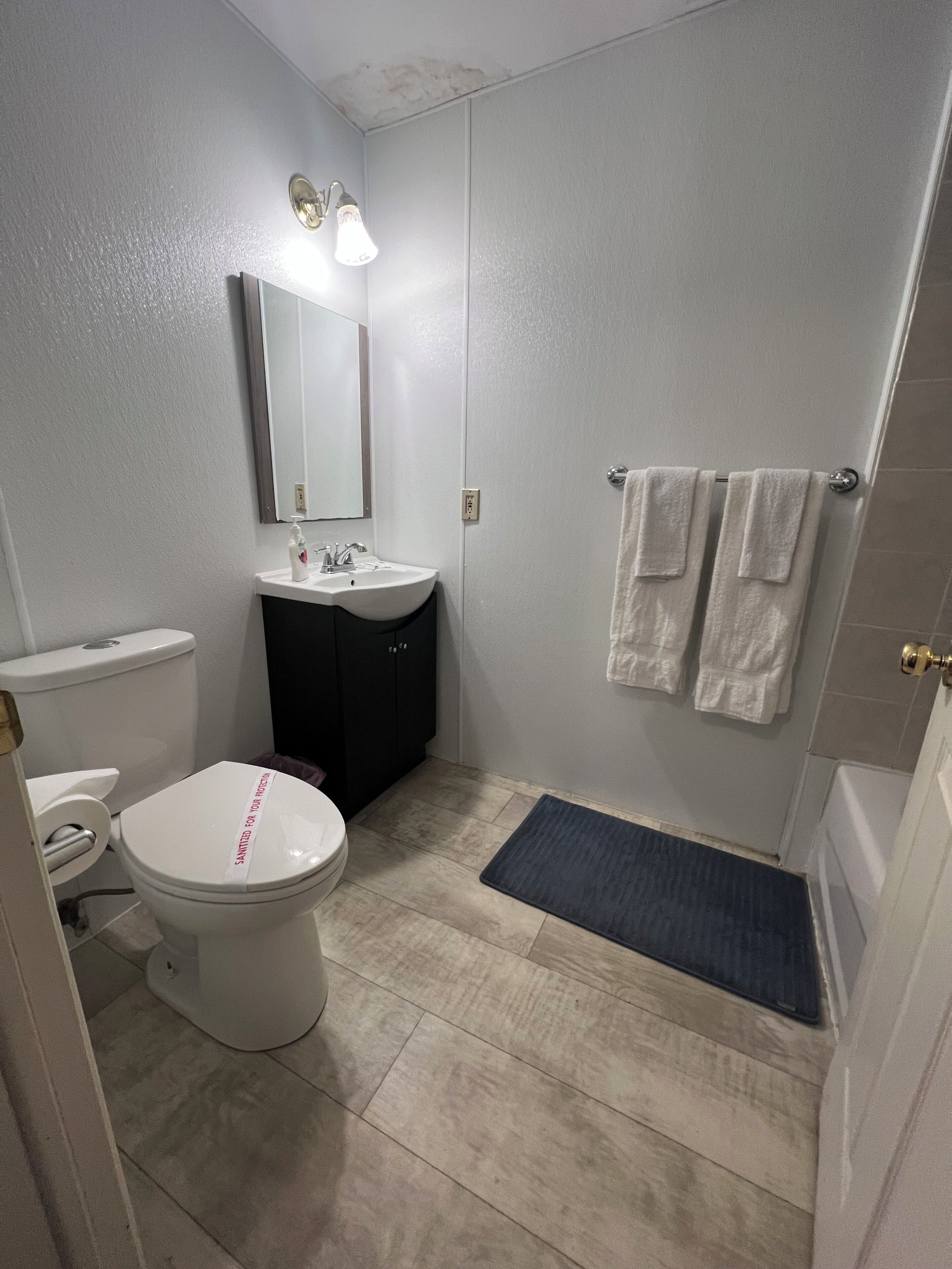 A bathroom with a toilet, sink, mirror, and towel rack.
