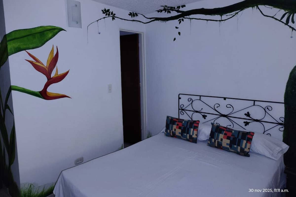 Ein Schlafzimmer mit Bett, Tür und Wandbildern.