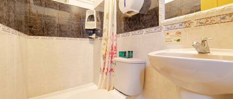 A bathroom with a toilet, shower, and sink.