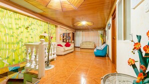 Un amplio espacio habitable con techo de madera, un sofá, un sillón azul y una estantería.