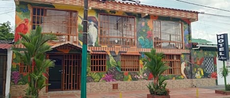 A hotel with a colorful mural, large windows, and a sign indicating a parking area.