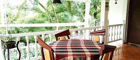 A balcony with a table and chairs, surrounded by lush greenery.