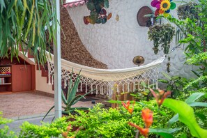 A hammock suspended between two columns in a lush indoor garden with a variety of plants and a bookshelf. - Hotel Eclipse Villavicencio (Villavicencio)