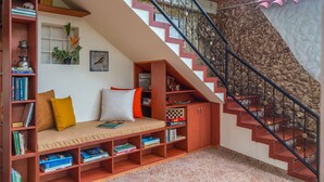 Un rincón acogedor para leer con un banco empotrado, estanterías y una escalera con barandillas decorativas.