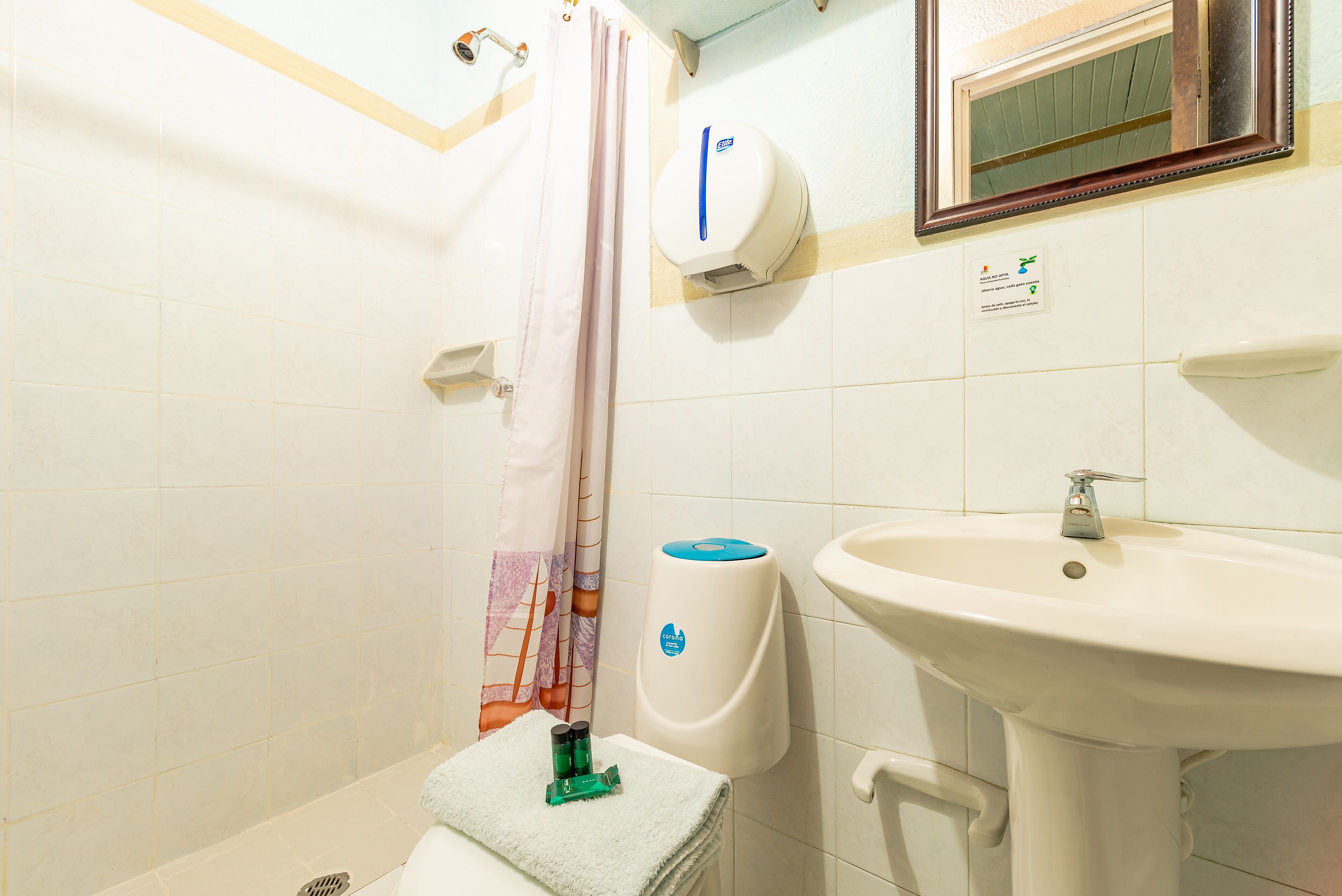 A bathroom with a white sink, a hand dryer, and a shower curtain.