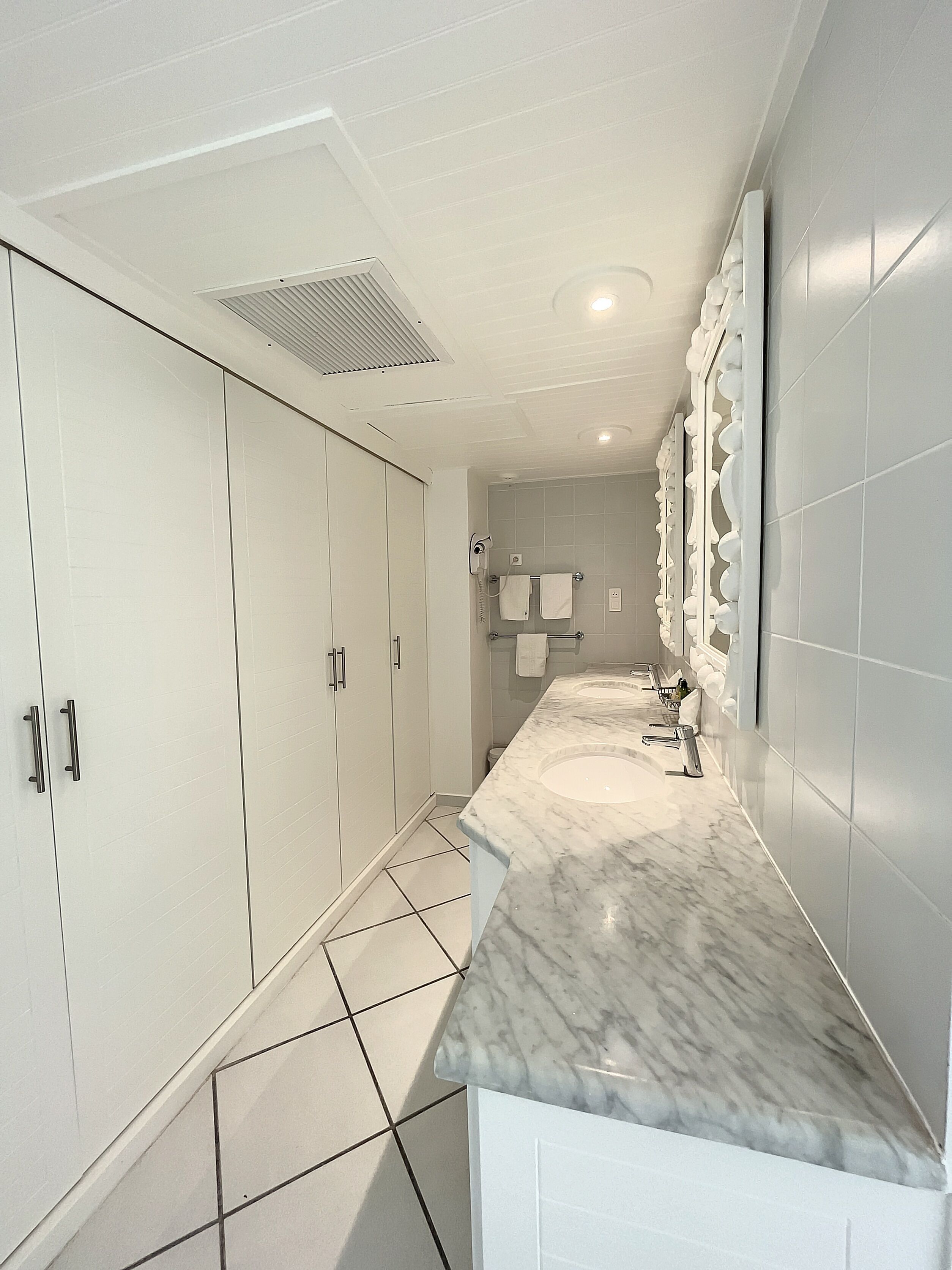 Une salle de bain moderne avec un plan de toilette en marbre, un lavabo intégré et un miroir fixé au mur.