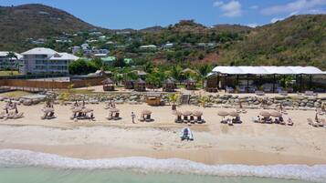 Un resort frente al mar con varias cabañas y una playa de arena, con montañas al fondo.