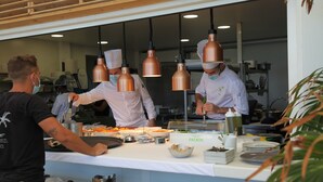 A kitchen area with chefs preparing food, copper pendant lights, and a counter with dishes and a bottle of tequila. - Le Domaine Anse Marcel Beach Resort (Anse Marcel)