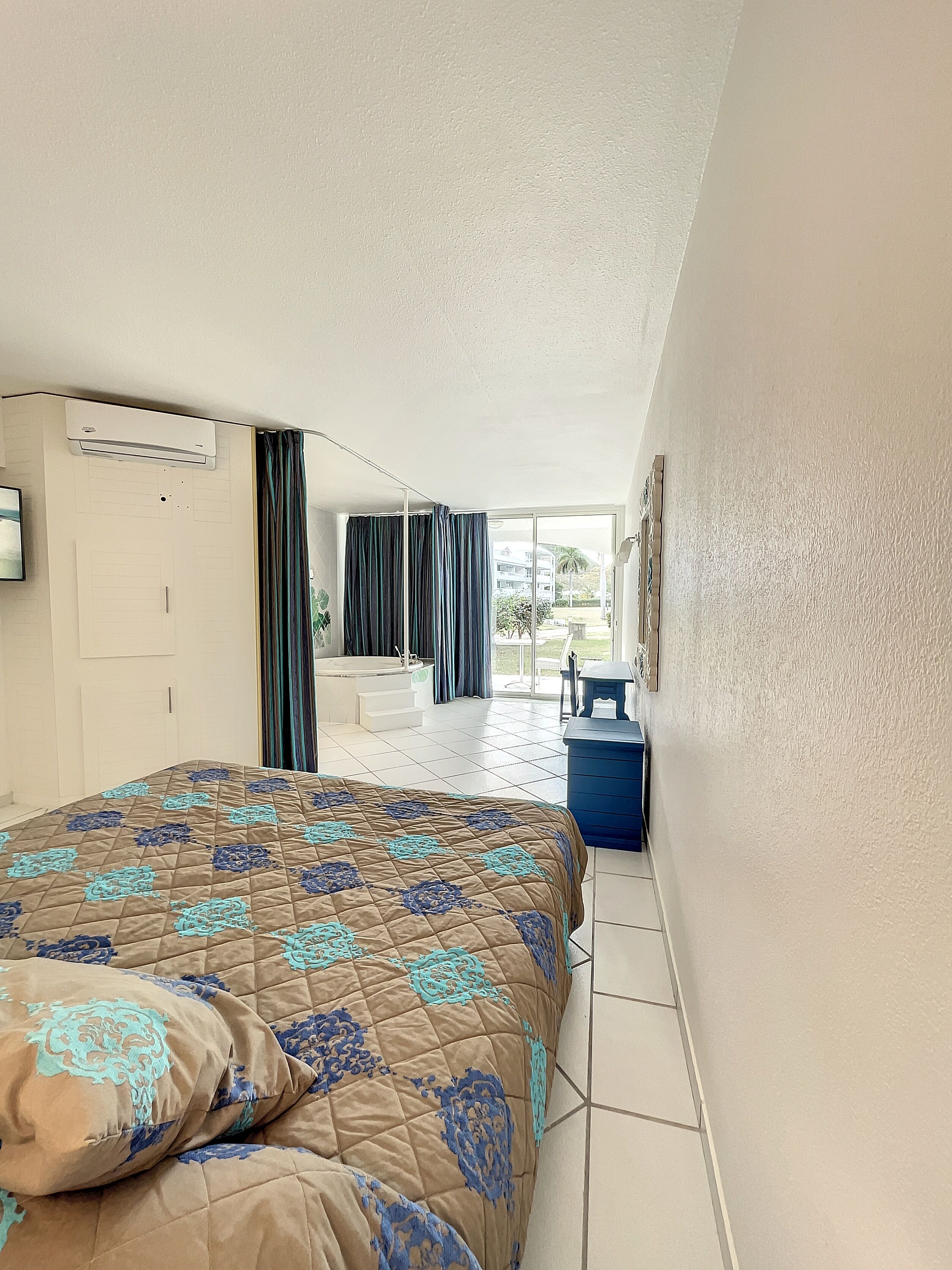 A hotel room with a bed, a desk, a chair, and a view of the outside.