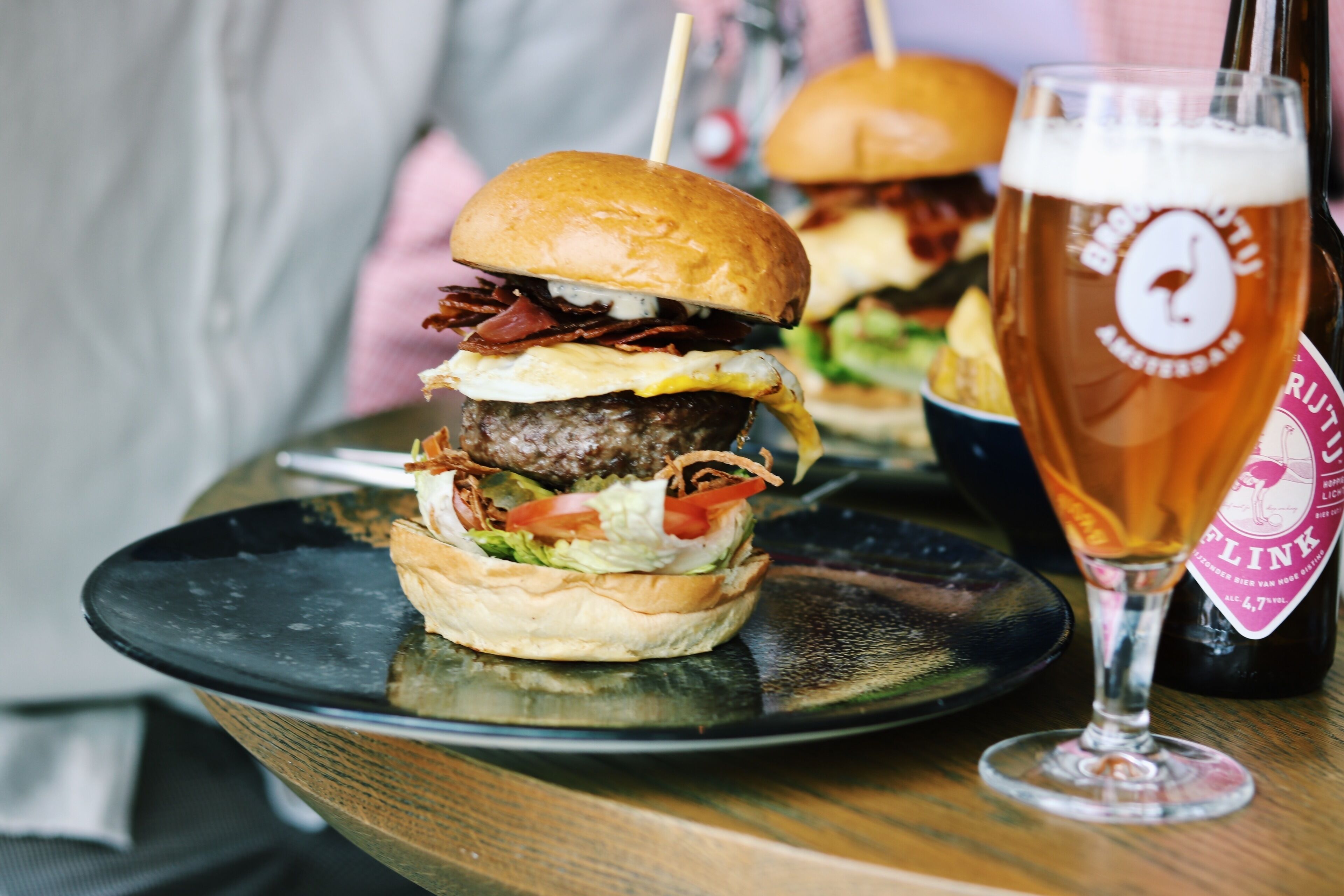 Una hamburguesa acompañada de papas fritas y una cerveza en la mesa.