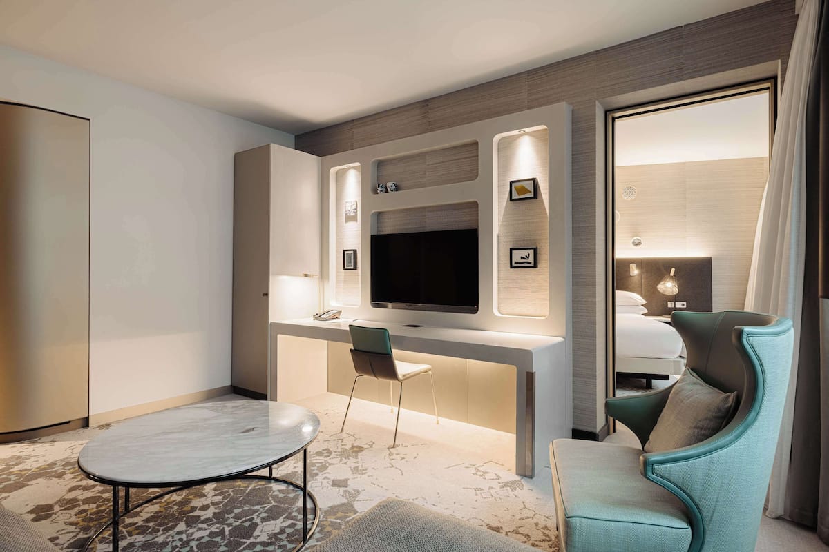 Una habitación de hotel moderna con televisión de pantalla plana, un escritorio con silla, un sofá y una cama.