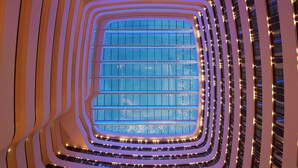 Un atrium à plusieurs niveaux, doté d’une structure centrale en verre et de nombreux balcons.