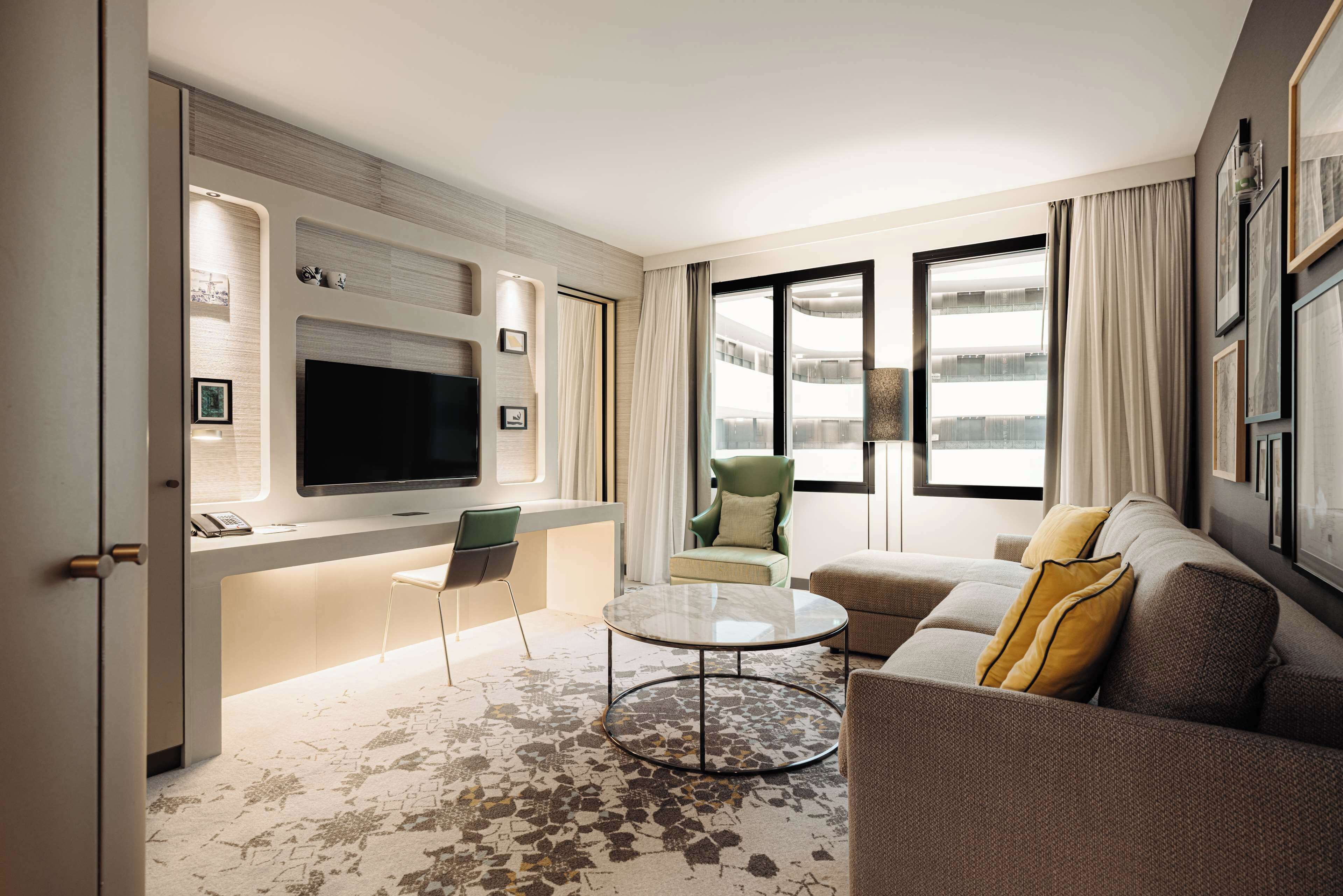 A modern living room with a flat-screen TV, a sofa, a coffee table, and a chair.