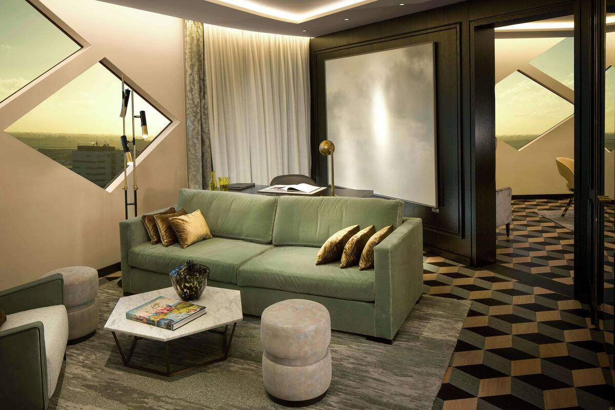 Una sala moderna con un sofá verde, una mesa de centro y vistas al campo a través de un amplio ventanal.