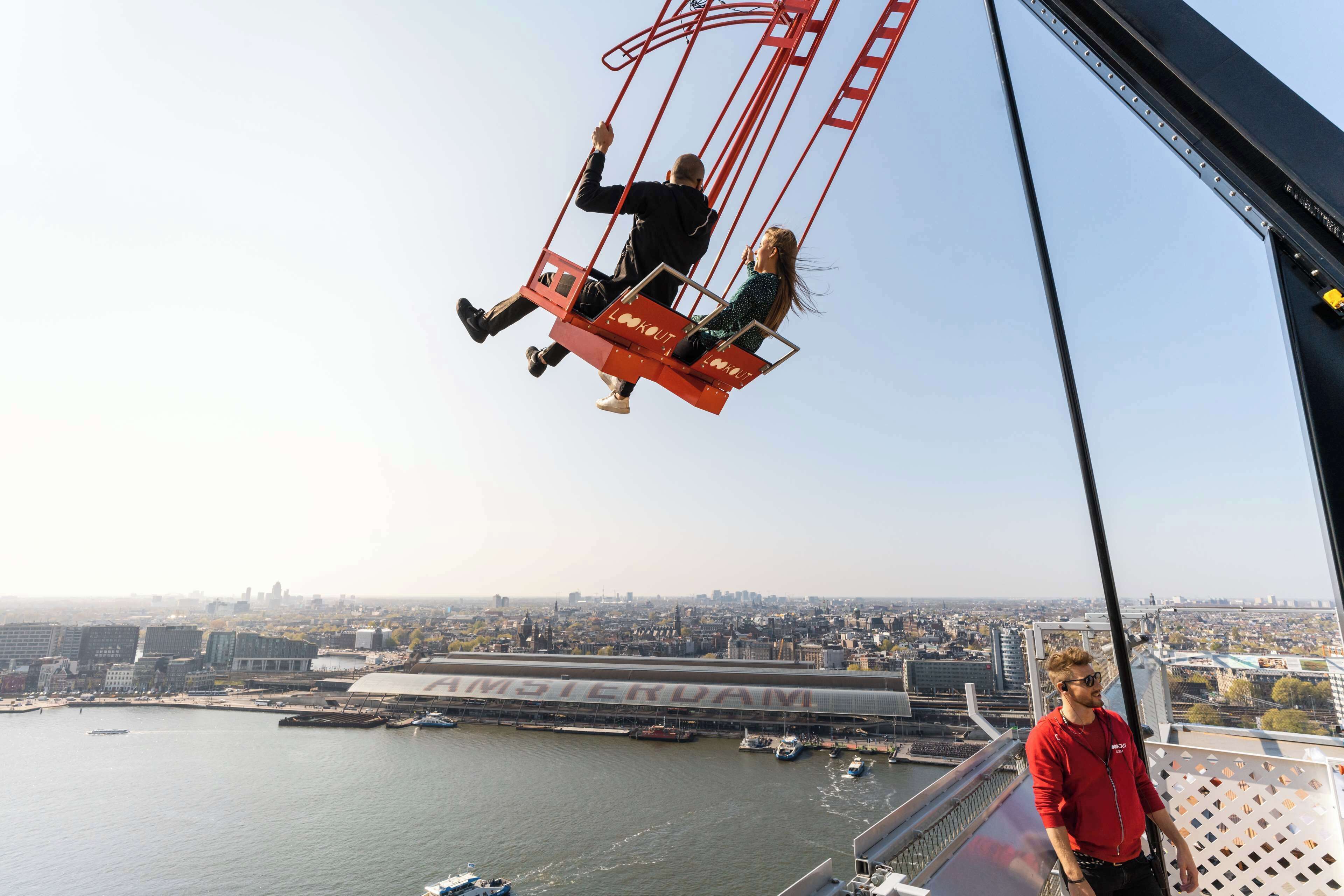A high vantage point overlooking a cityscape with a bridge labeled "AMSTERDAM" and a body of water with boats.