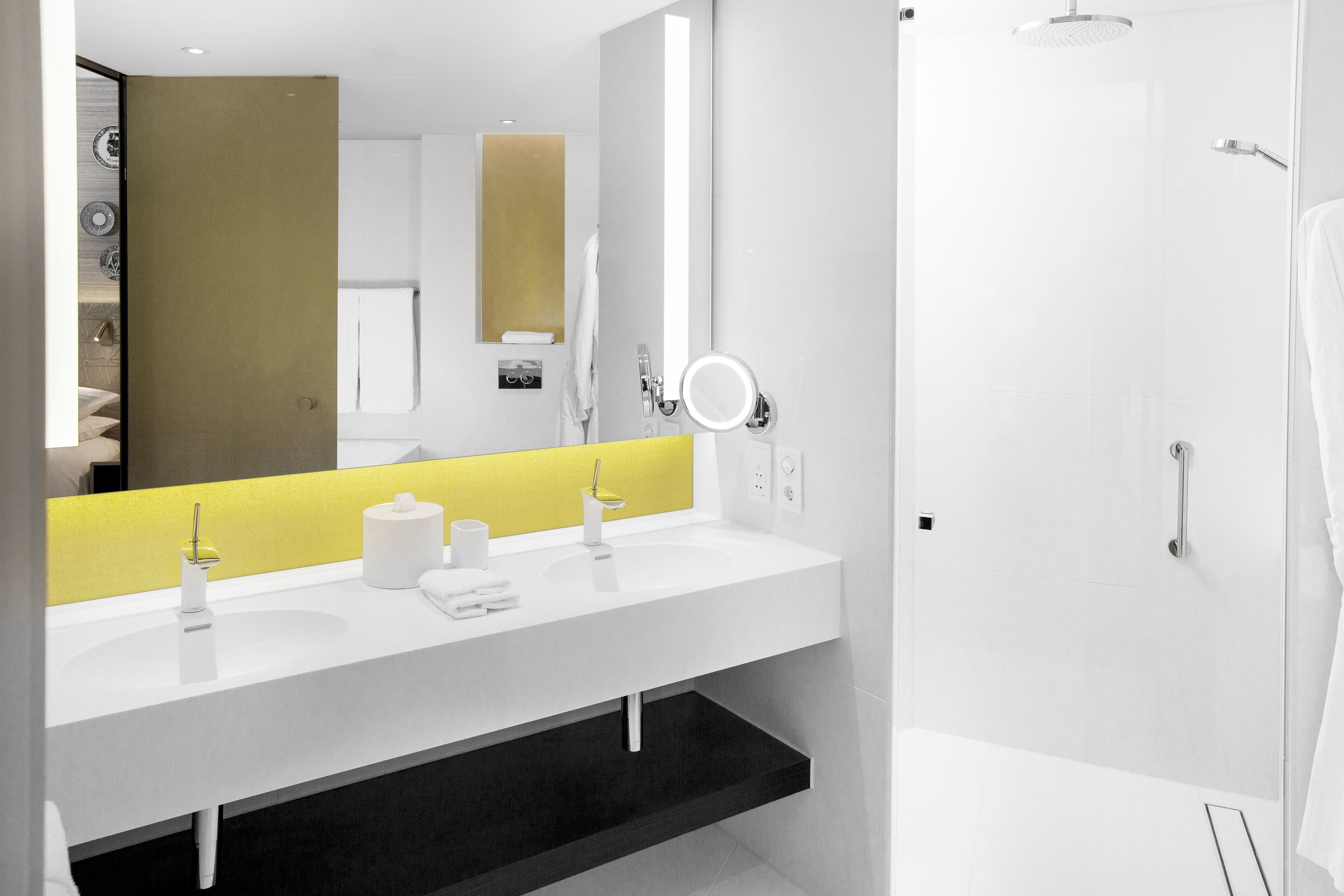 Un baño moderno con un lavamanos blanco, una pared de acento amarilla y un espejo grande.