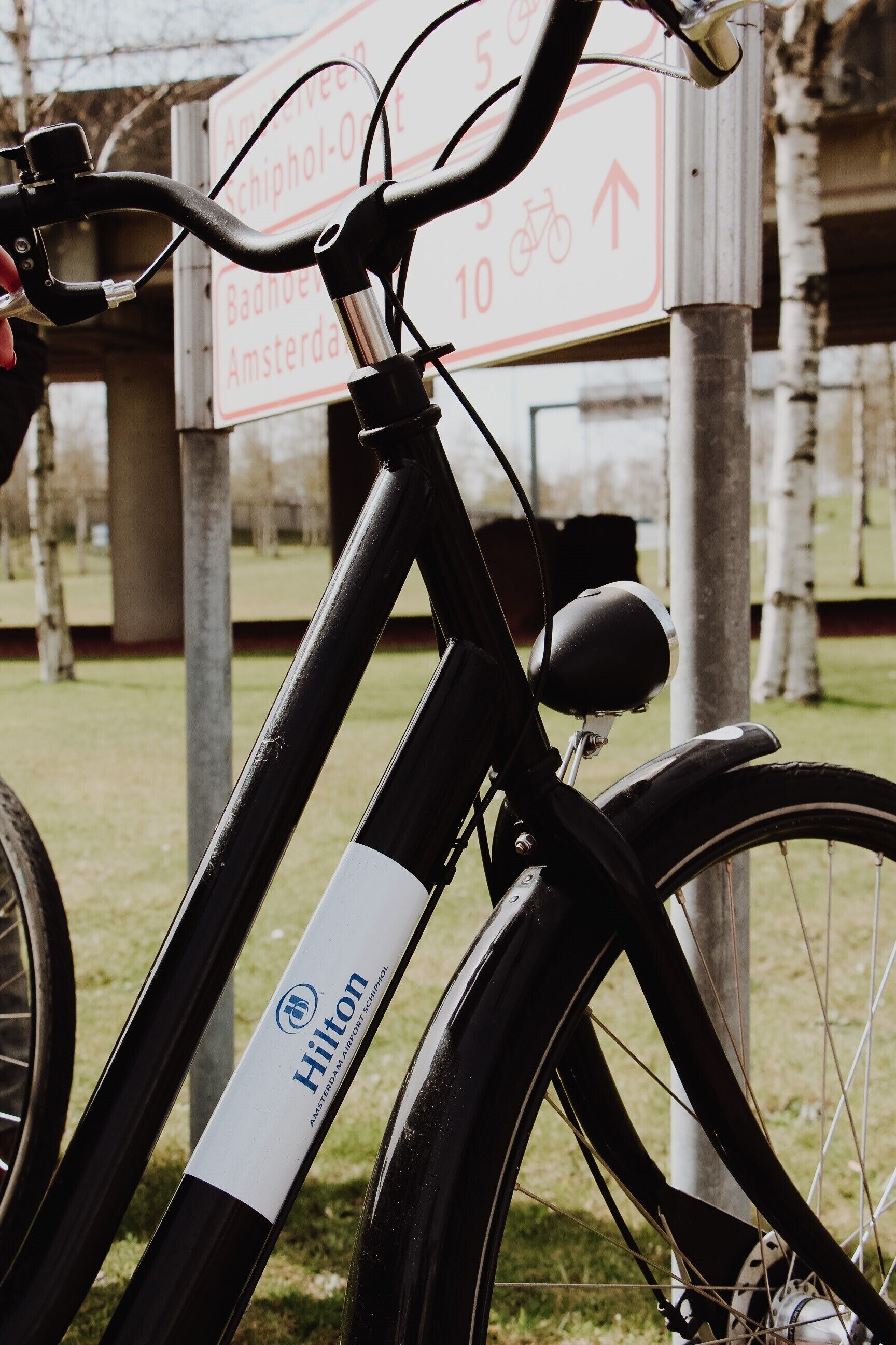 Een fiets met een 'Hilton' logo, een richtingsbord en een gazon.