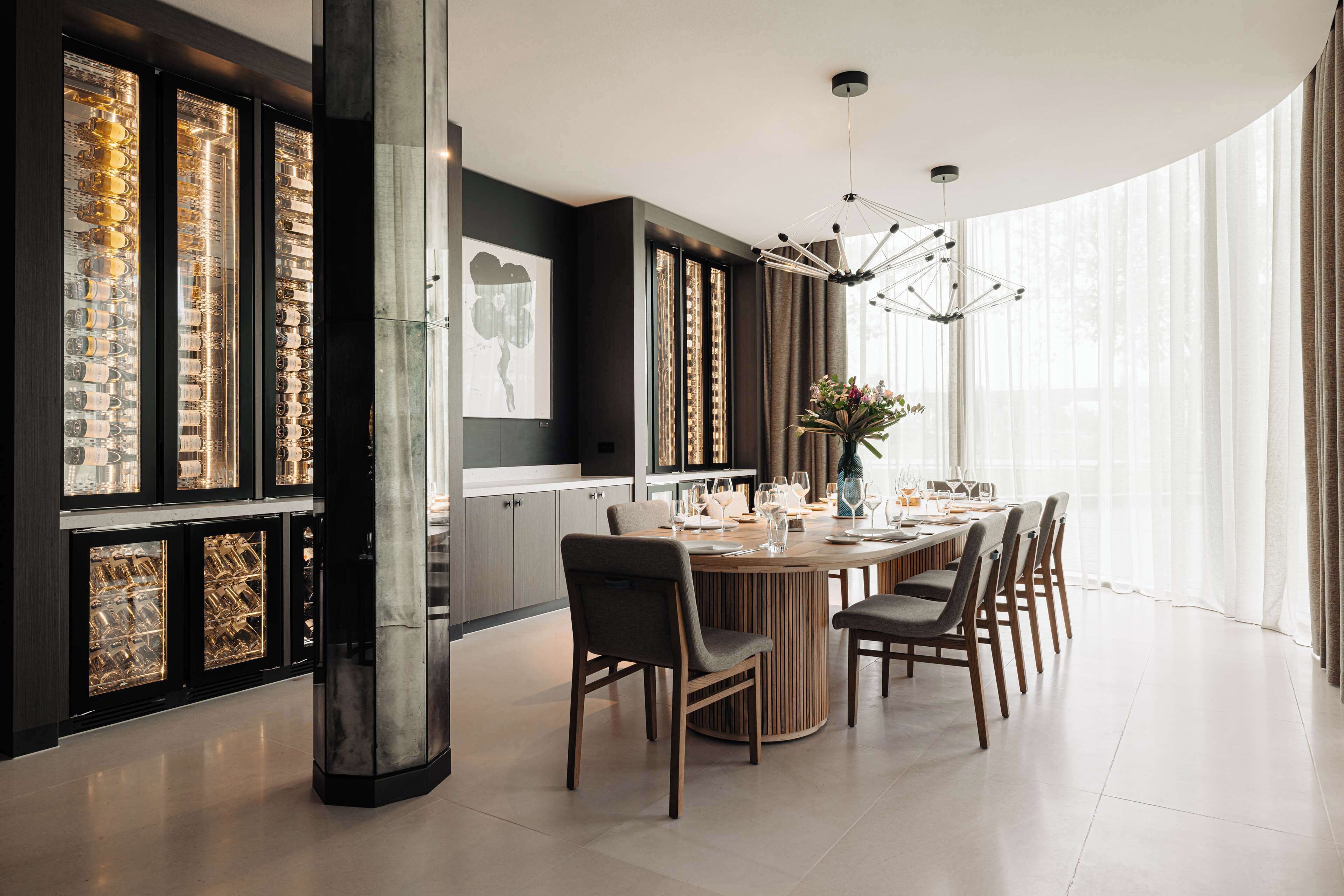 A modern dining area with a round table, chairs, and a chandelier.