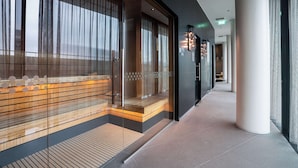 A modern hotel corridor with glass partitions, wooden benches, and a tiled floor. - Hilton Amsterdam Airport Schiphol (Schiphol)