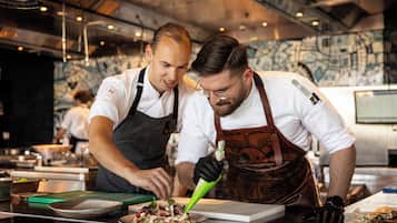 Two chefs preparing food in a modern kitchen with industrial design elements.