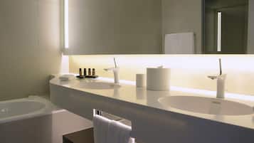 A modern bathroom with two sinks, a large mirror, and a towel rack.