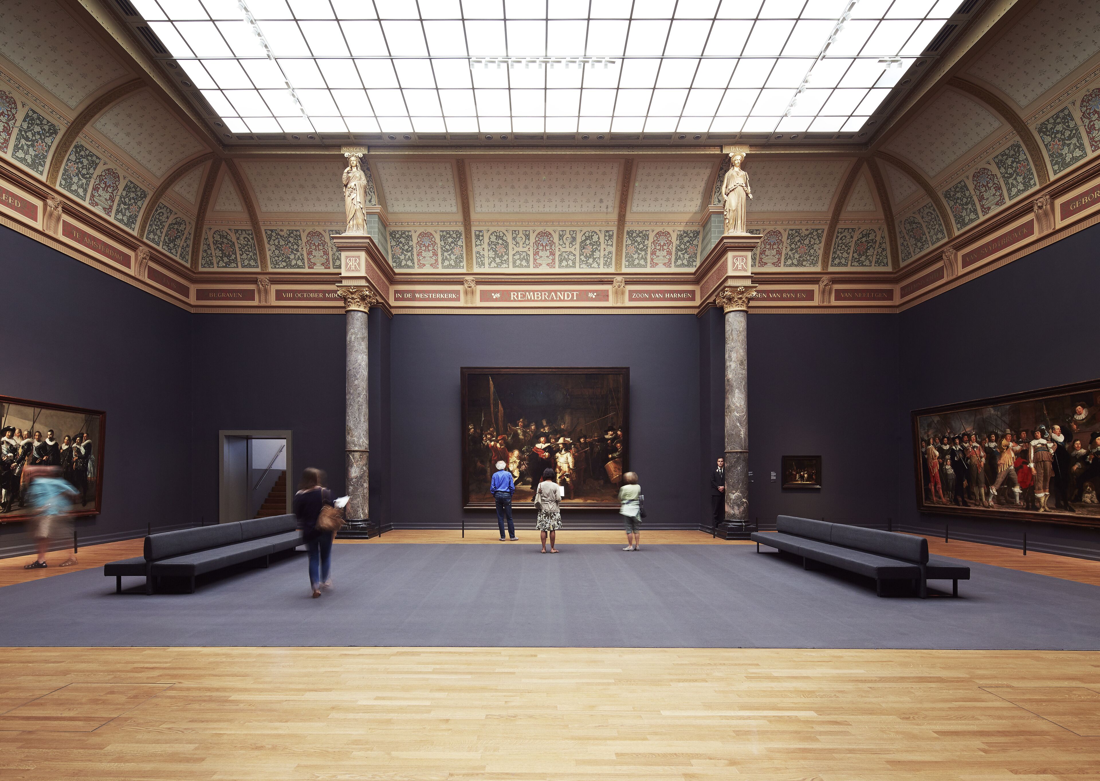 Uma galeria de arte com arquitetura clássica, grandes pinturas e colunas de mármore.