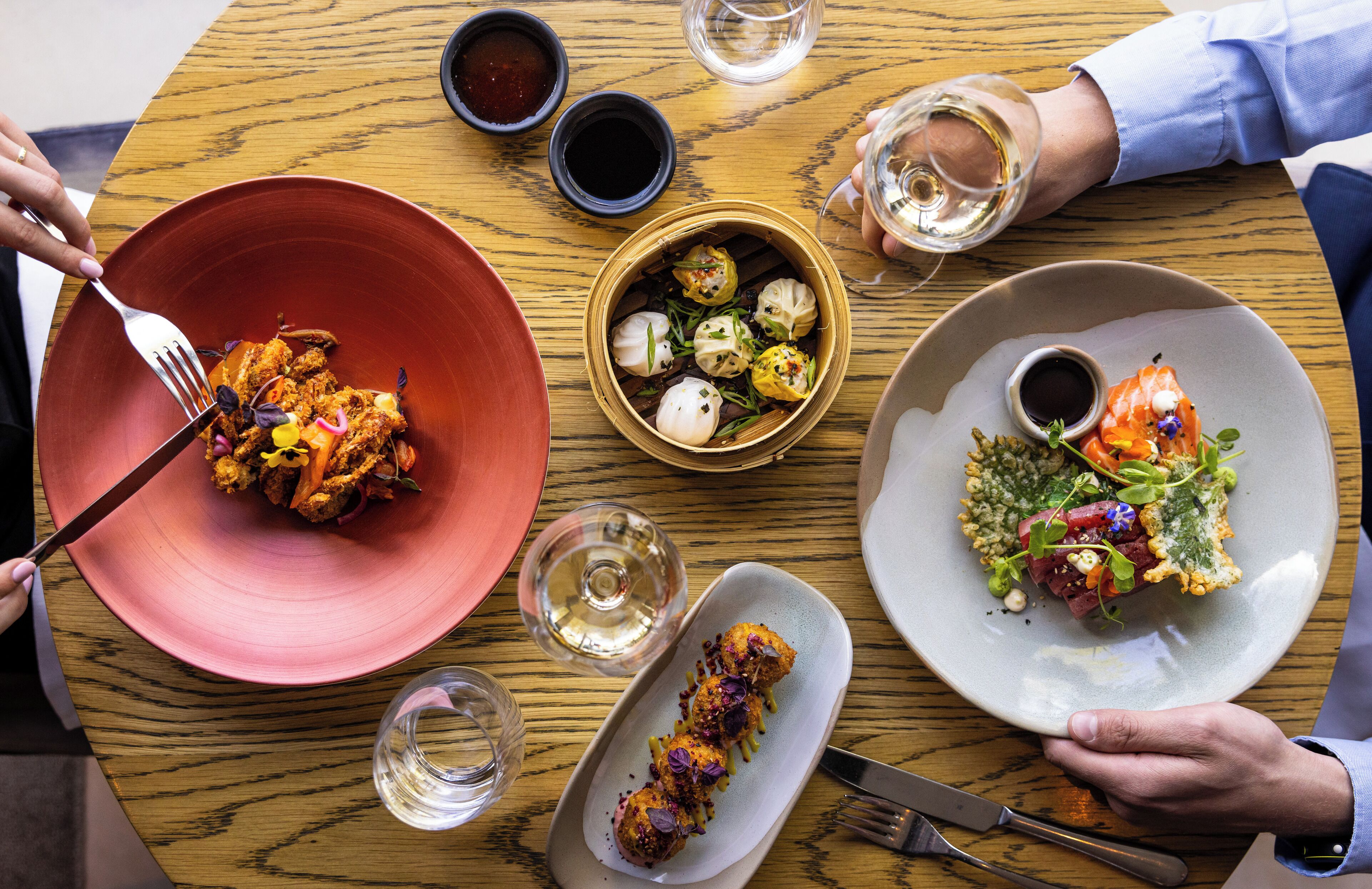 Una mesa de comedor con varios platos, cubiertos y vasos.