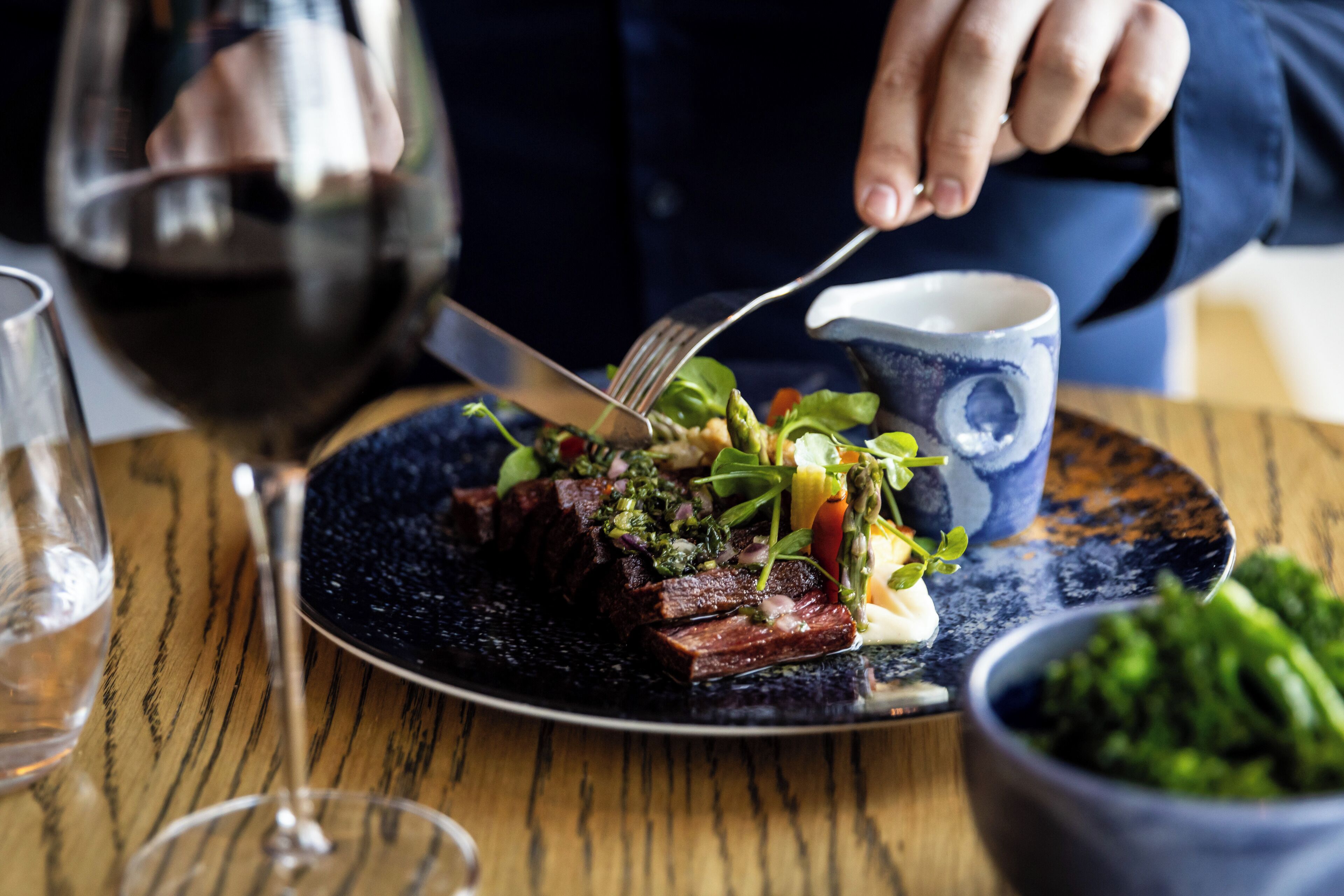 A dining table with a plate of food, a glass of wine, and a cup.