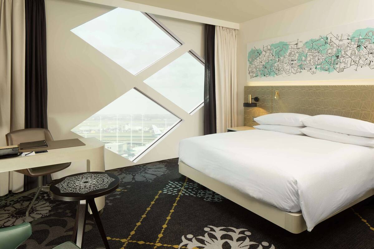 Una habitación de hotel con cama, escritorio, silla, ventana y un mapa en la pared.