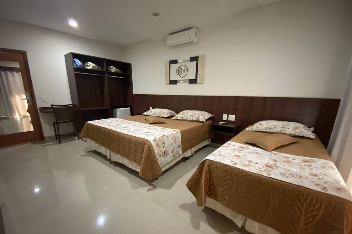 A hotel room with two beds, a desk, and a wardrobe.
