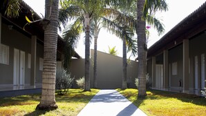 A pathway flanked by palm trees leading to a building with a flat roof and white-framed windows. - Hotel Dolce Dulce (Olímpia)