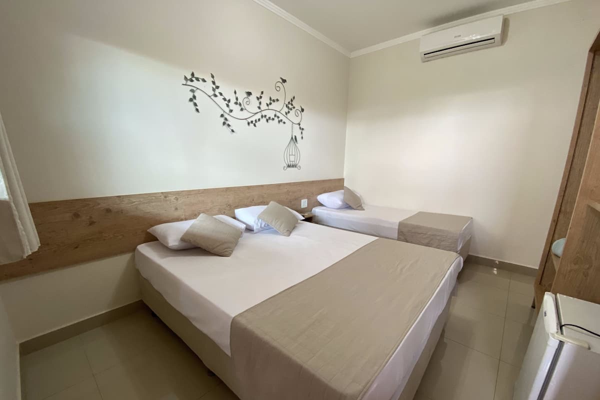 A hotel room with two beds, a wooden headboard, a wall decoration, and an air conditioning unit.