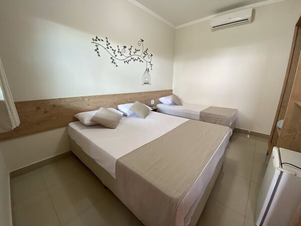 A hotel room with two beds, a wooden headboard, a wall decoration, and an air conditioning unit. - Hotel Dolce Dulce (Olímpia)
