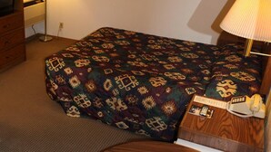 A hotel room with a bed, a wooden nightstand, a lamp, a telephone, and a framed picture on the wall. - Yorkshire Motel (York)