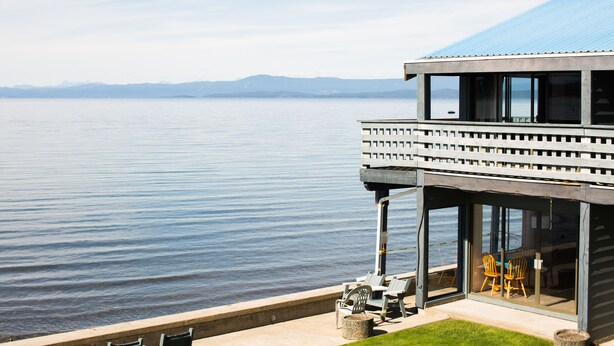 Un bâtiment situé au bord du lac, doté d’un balcon, d’un espace salon et offrant une vue sur l’eau.