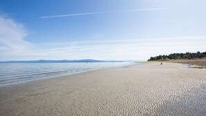 Une vaste plage de sable fin, avec des eaux calmes et un ciel dégagé.