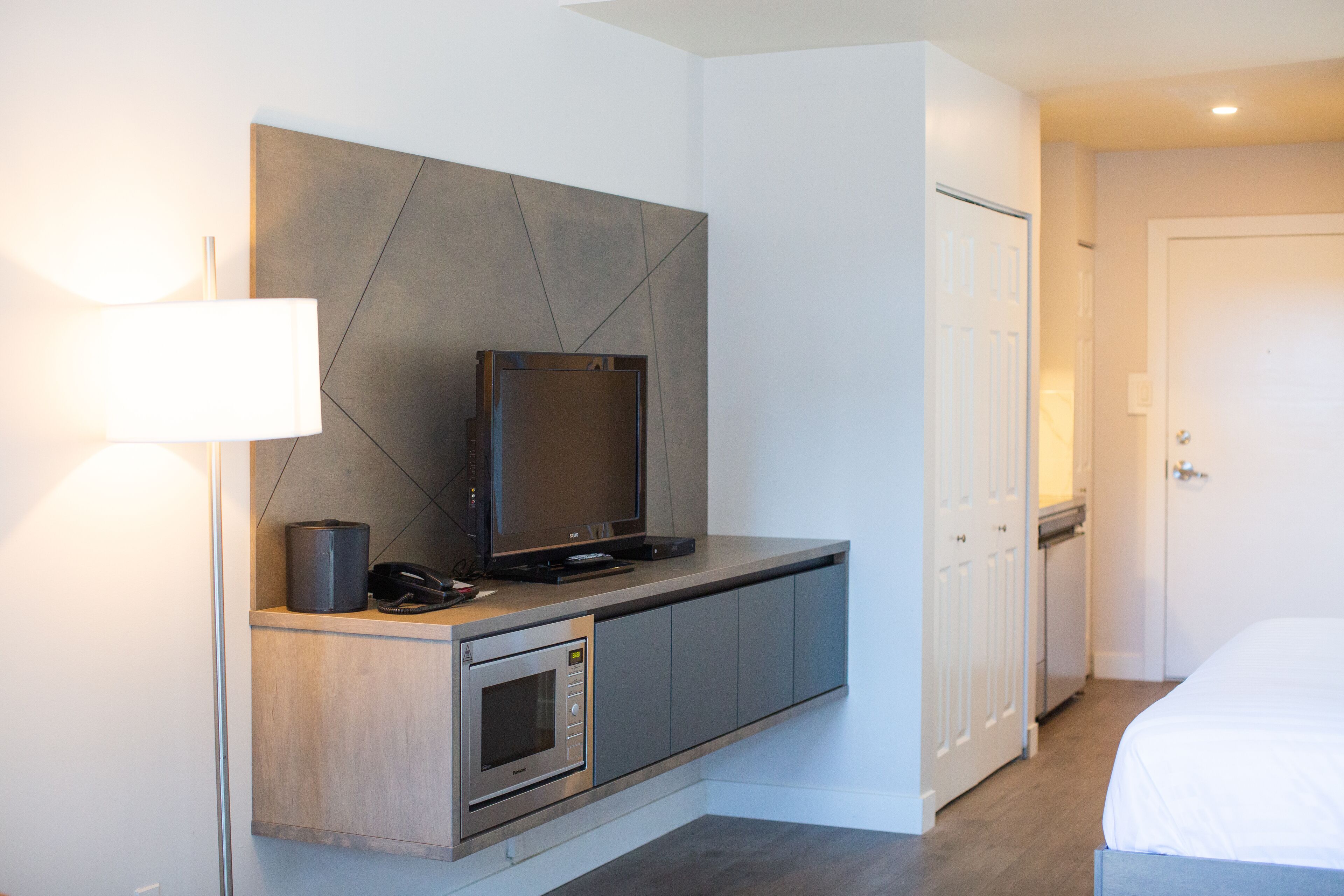 Una habitación de hotel moderna con televisión integrada, microondas y mesita de noche.