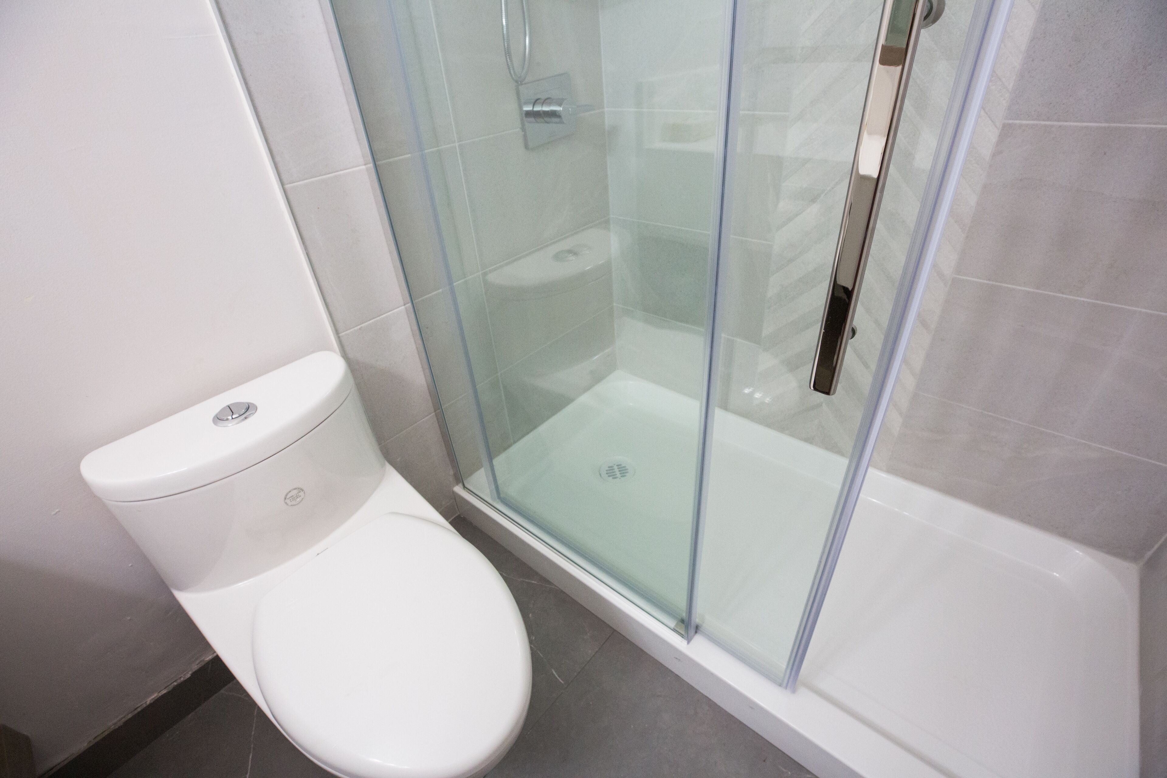 A modern bathroom with a glass-enclosed shower, a white toilet, and a tiled floor.