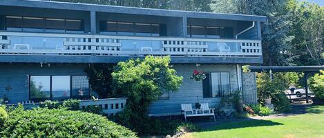 A two-story house with a balcony, large windows, and a garden area.