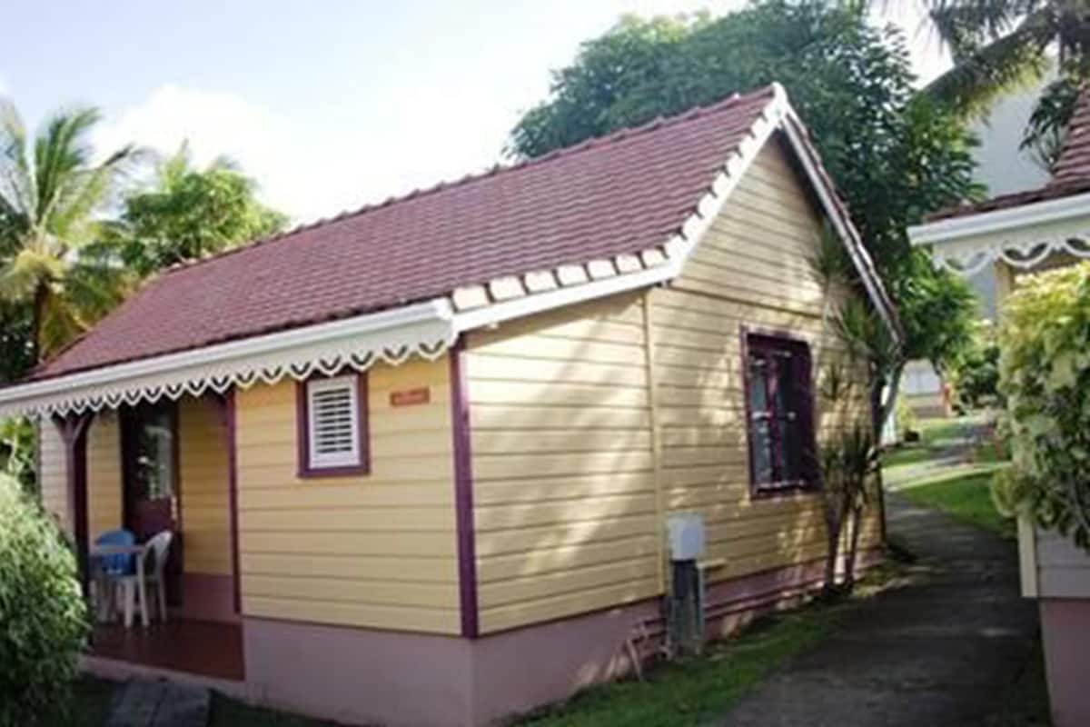 A small, single-story building with a red-tiled roof and a porch with a white trim.