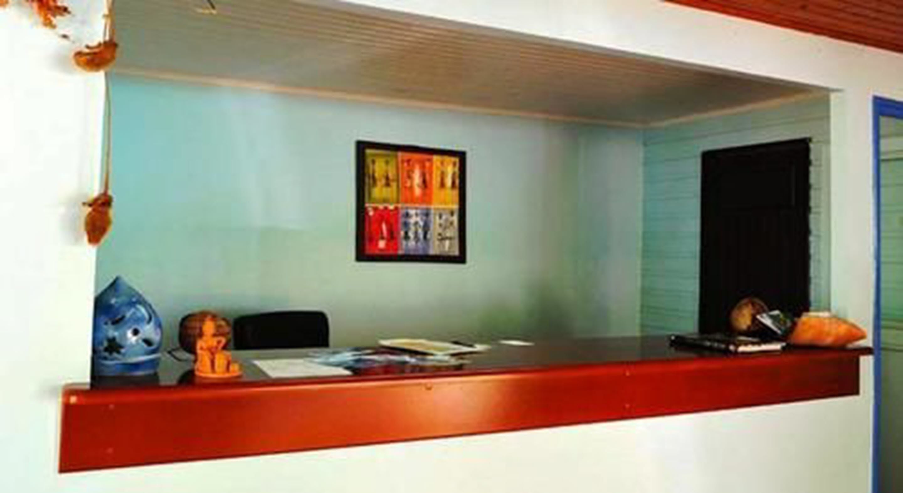 A reception desk with a framed artwork above it, a small statue, and a few items on the counter.