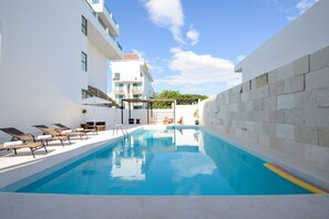 Una piscina con sillas de descanso, una pérgola y un muro de piedra.