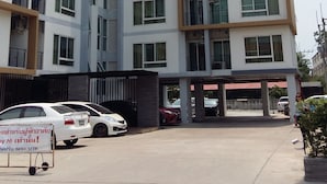 Un edificio residencial de varios pisos con balcones, un estacionamiento techado y un letrero.