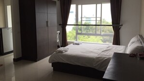 Una habitación de hotel con una cama grande, un armario y una ventana con cortinas.