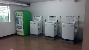 Cuatro dispensadores de agua alineados en una habitación con suelo de baldosas y ventana.