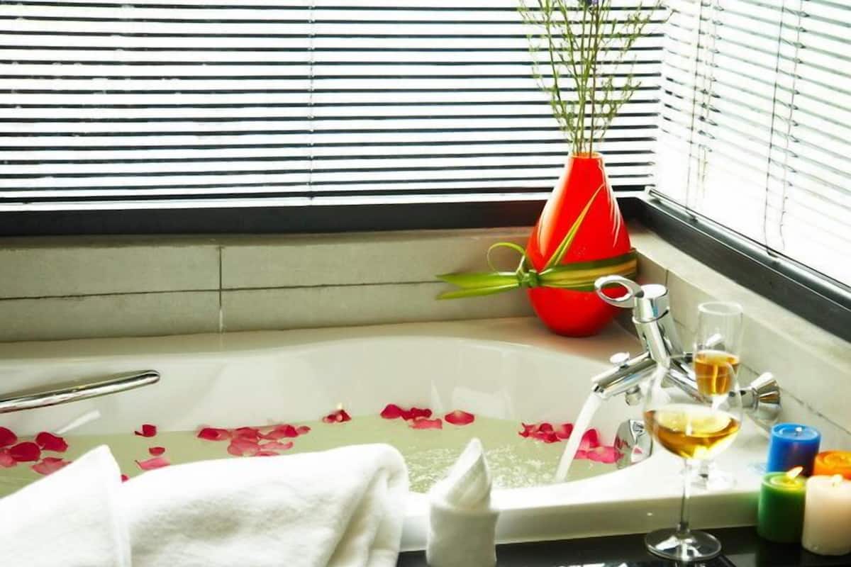 A bathroom with a bathtub, a towel, a glass of wine, and candles.