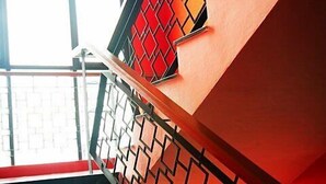 Escada com parede estampada em padrão geométrico e guarda-corpo de metal.