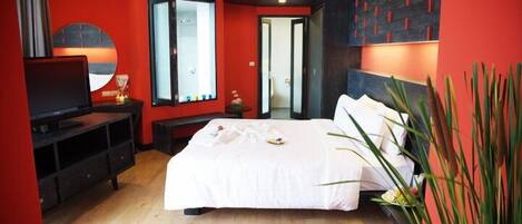 Une chambre d’hôtel moderne avec un grand lit, une télévision et un mur d’accent de couleur rouge.